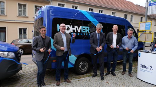 Fünf Männer, die vor dem MOHVER-Kleinbus stehen, zerschneiden ein blaues Band.