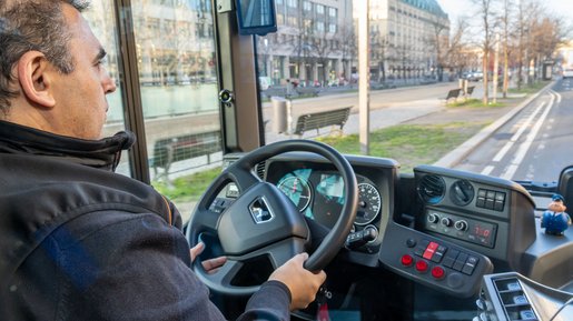 Busfahrer am Steuer blickt durch die Frontscheide auf die Straße.