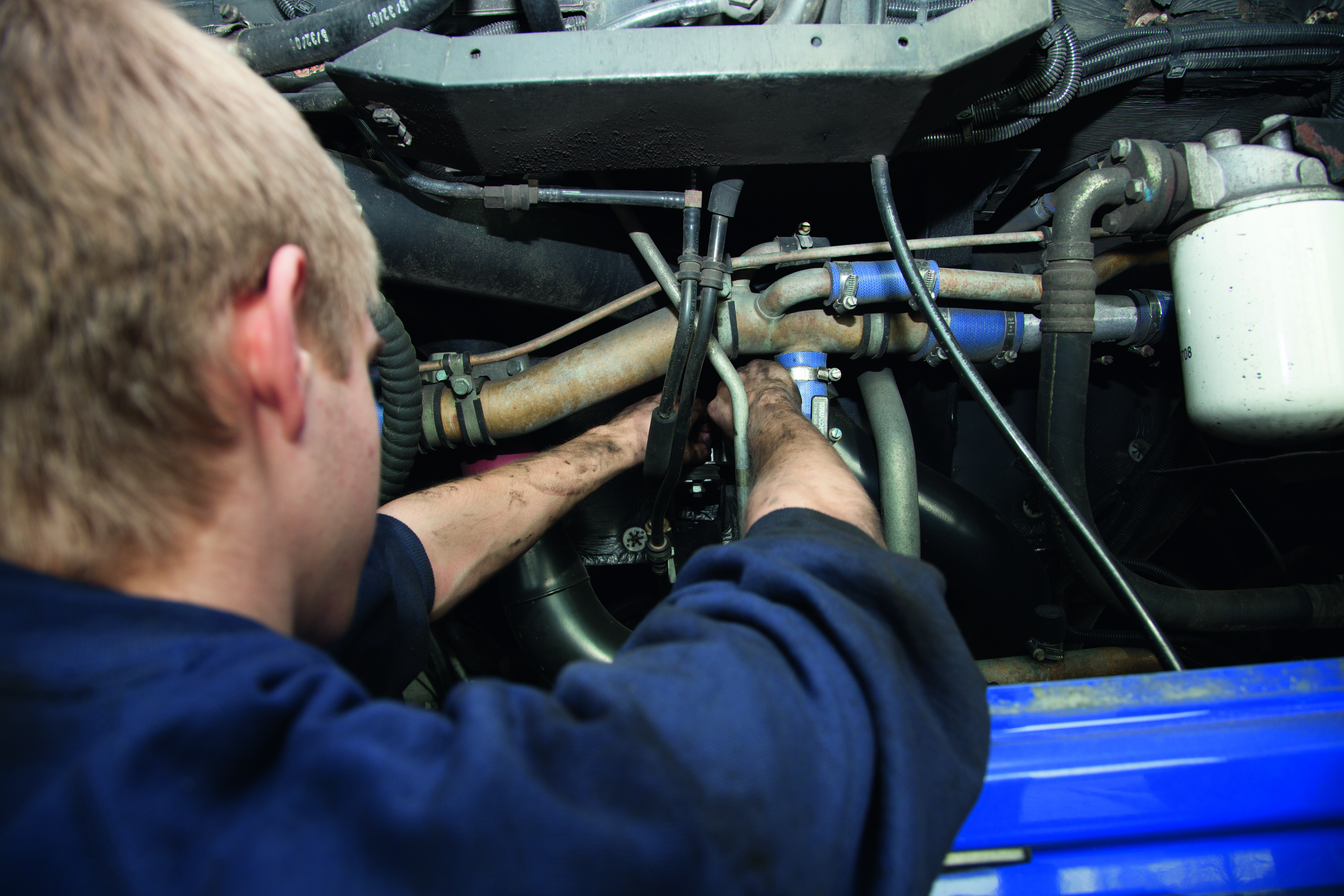 Junger Mensch schraubt an einem offenen Busmotor